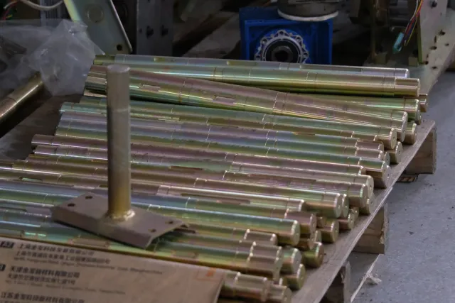 Rows of metal shafts laid out on cardboard in the barrier workshop