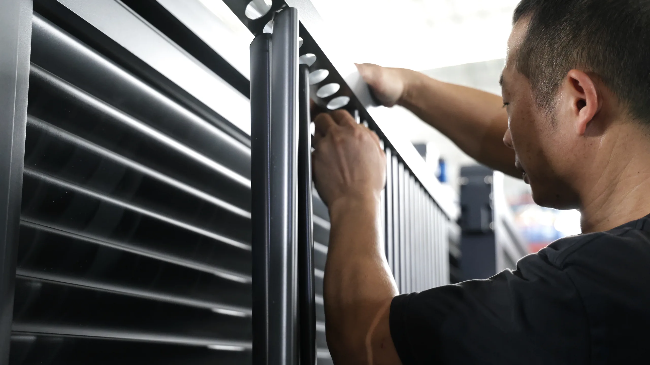 A Hengbo worker fitting the upper connection of a gate panel on the factory assembly floor